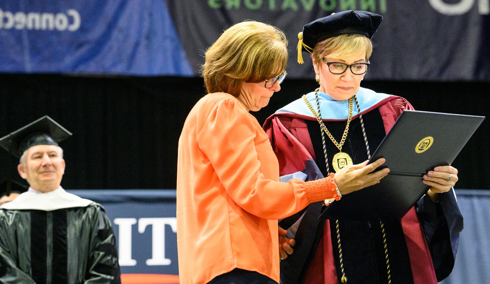 Valerie Fadigan accepts degree forher nephew, John Paul 'JP' Ramel.