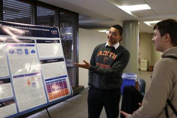 A student makes a presentation by a poster at the 2024 学生 Conference for 研究, Professional Activities, 及创意艺术.