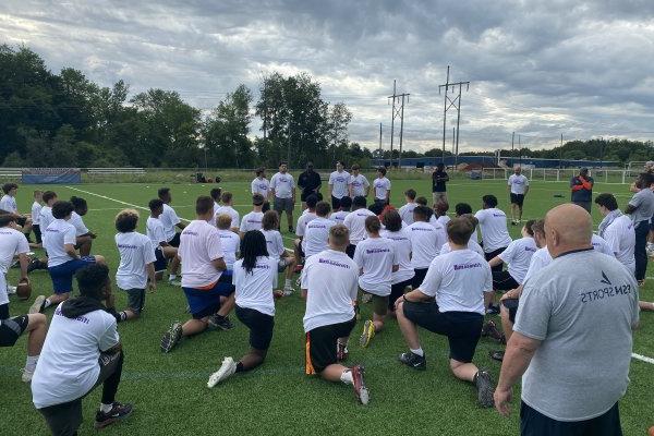 Participants kneel on the football field.