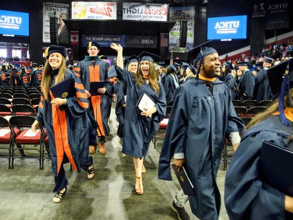 A graduate waves as members of the graduate class of 2022 exits the ceremony with their degrees.